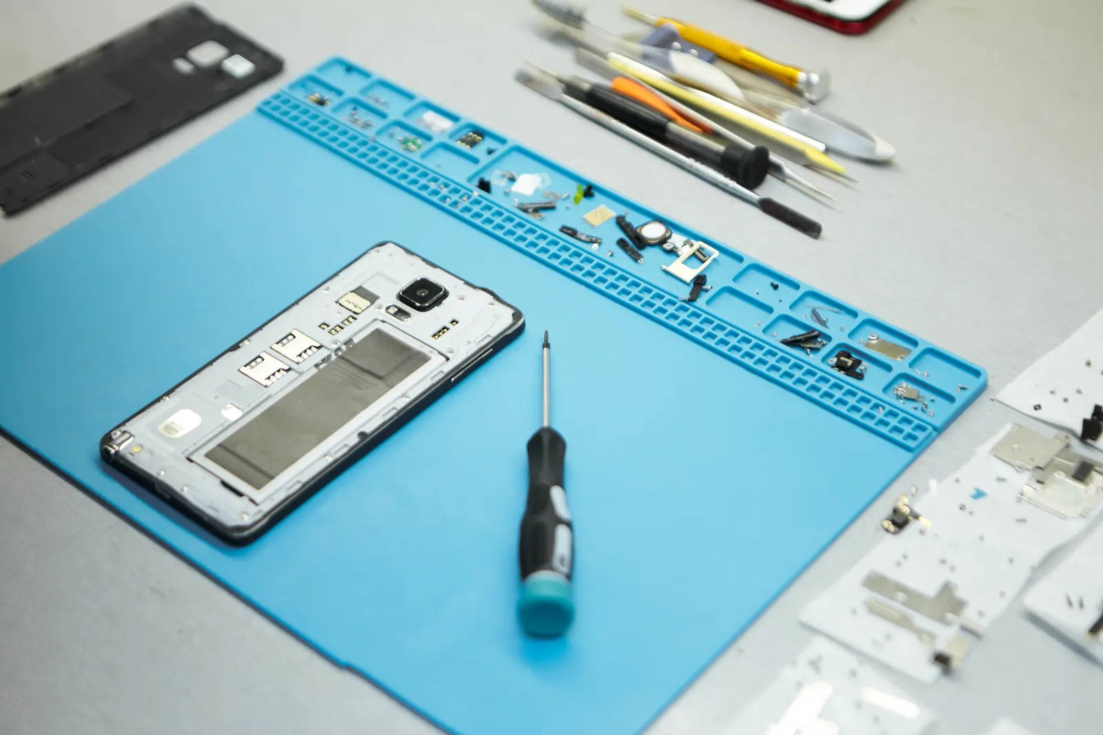 A phone opened up on a repair bench with precision tools